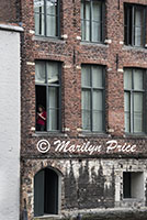 Woman texting in an open window, Bruges, Belgium