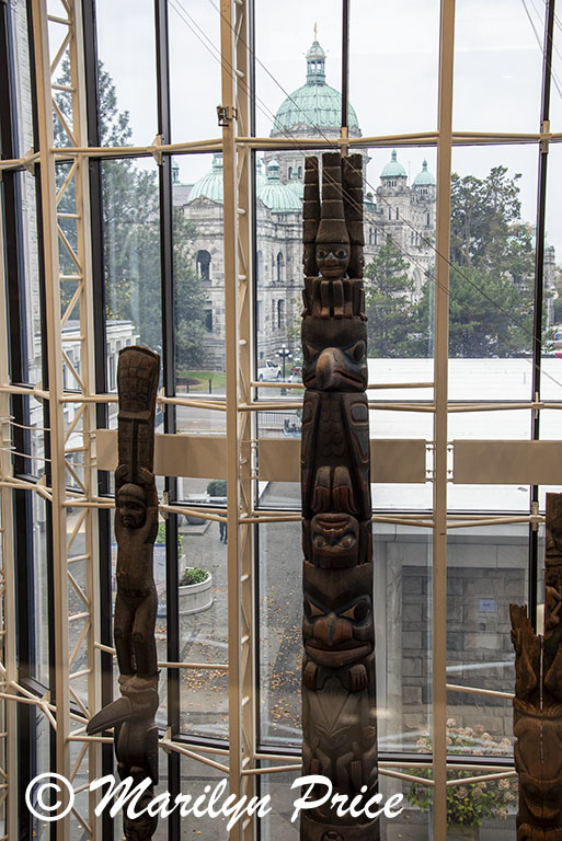 Totem poles in the Royal British Columbia Museum with provincial buildings in background, Victoria, BC, Canada