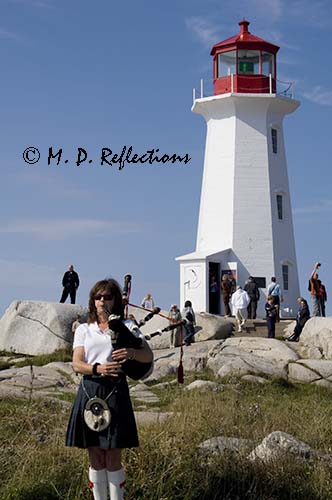 A piper entertains at the Light at Peggy's Point, Peggy's Cove, Nova Scotia